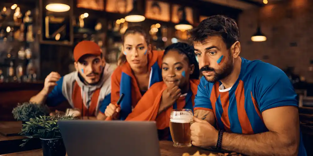 fans watching football in a pub on a laptop