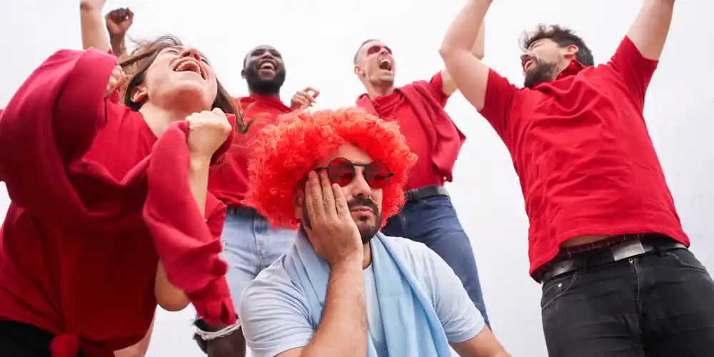 one upset fan sitting infront of cheering fans