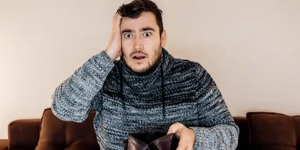 regretful man showing empty wallet