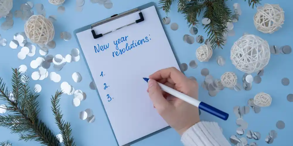 a hand is writing new year resolutions
